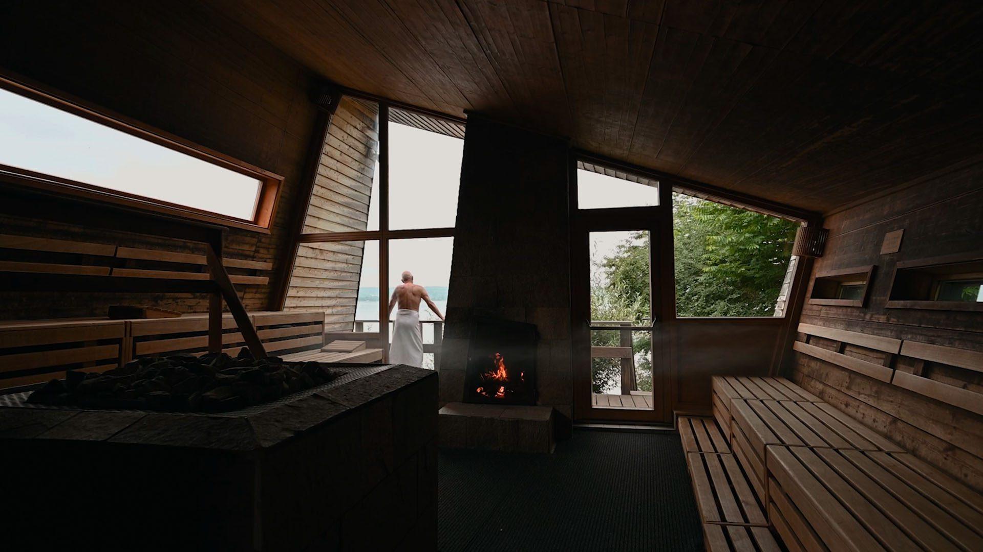 Mann steht vor Panorama Sauna und schaut auf den Bodensee – Szene aus einem Imagefilm für die Therme Überlingen in Kooperation mit b.lateral, produziert von Charlie Grashoff - The C/A Studio, Videoproduktion in Leipzig. Projekte deutschlandweit. Imagefilme, Corporate Videos, Brandfilme, Eventfilme, Industriefilme & mehr.