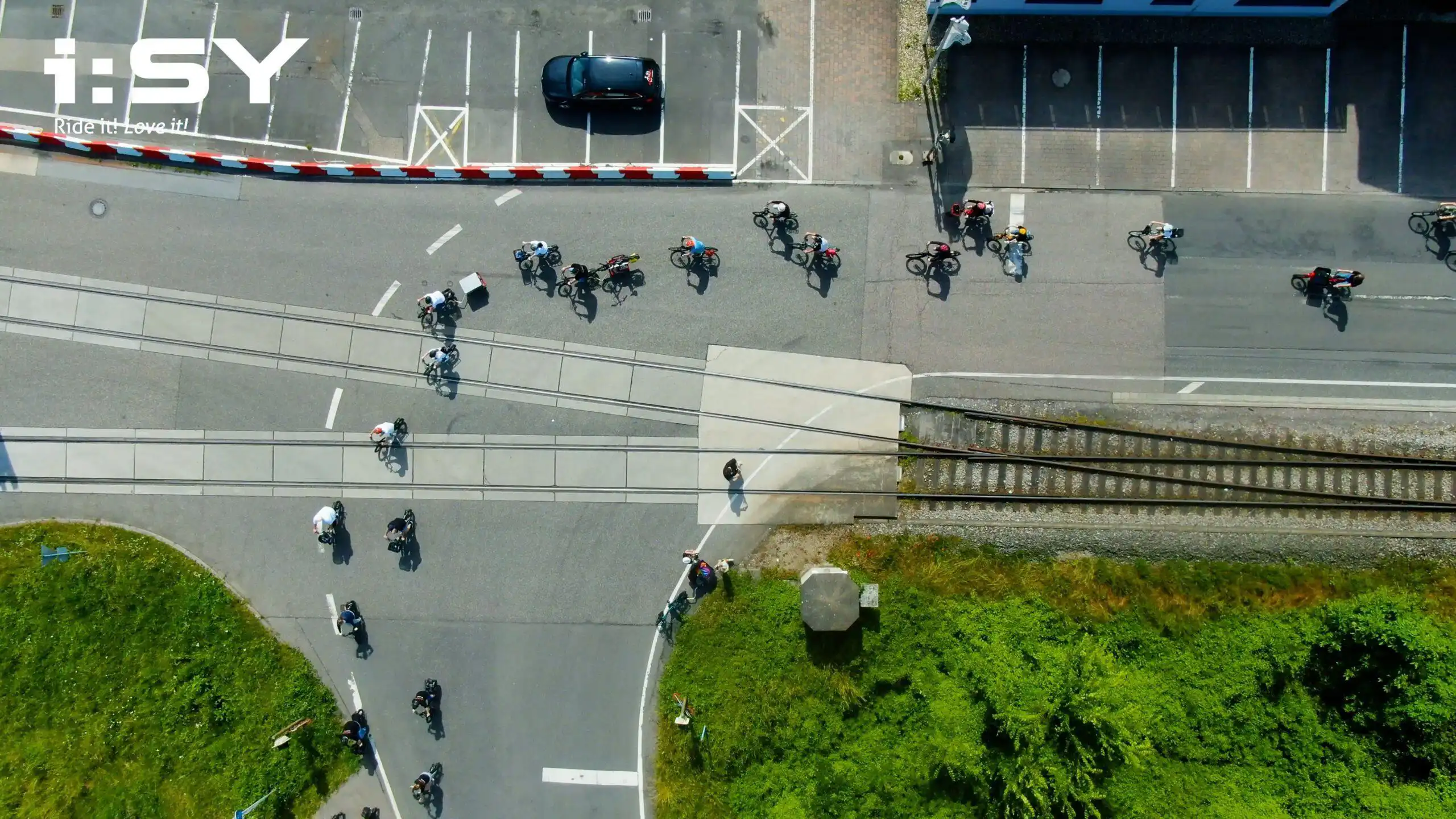 i:SY Treffen 2023, viele Fahrer:innen fahren durch Industriegebiet mit ihrem i:SY, Drohnenaufnahme – Szene aus einem Eventfilm für die Firma i:SY GmbH & Co. KG, produziert von Charlie Grashoff - The C/A Studio, Videoproduktion in Leipzig. Projekte deutschlandweit. Imagefilme, Corporate Videos, Brandfilme, Eventfilme, Industriefilme & mehr. Eventvideo.